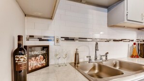 A kitchen with a wine bottle, a framed picture, and two wine glasses on the counter. - Adorable Intown Duplex Close to Downtown Atlanta; 5 minute walk to Beltline (Atlanta)