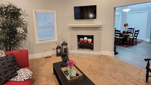 A living room with a red sofa, a black coffee table, a fireplace, and a TV mounted on the wall. - Adorable Intown Duplex Close to Downtown Atlanta; 5 minute walk to Beltline (Atlanta)