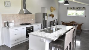 Una cocina moderna con armarios blancos, un refrigerador de acero inoxidable, una estufa a gas y una encimera de mármol.