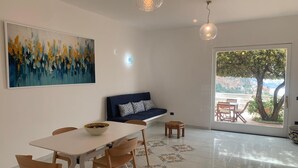 Un salon moderne comprenant un coin repas, un canapé et une grande fenêtre donnant sur des arbres, ainsi qu’un balcon.