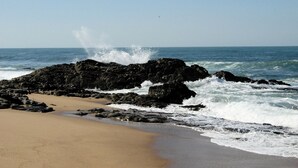 Una spiaggia con affioramenti rocciosi e onde che si infrangono sulla riva.