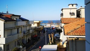 A narrow street with buildings on both sides, a clear blue sky, and a view of the sea in the distance. - Hotel Tiglio (Rimini)