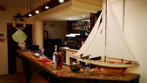 Une cuisine avec un petit modèle de voilier posé sur le comptoir, un panneau d’accueil et un coin bar avec des bouteilles.