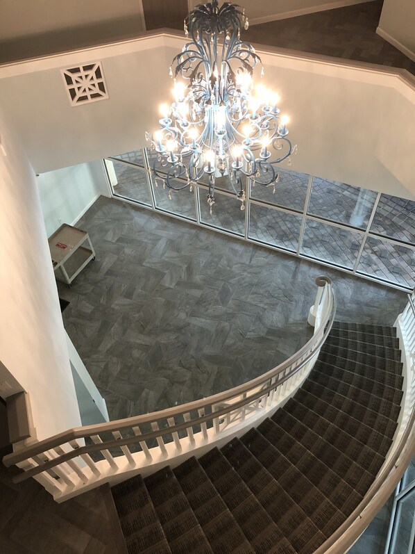 A spiral staircase with a modern design, a chandelier, and a herringbone-patterned floor.
