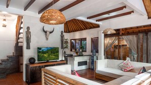 Amplia sala de estar con un banco de madera, un televisor y una pared de piedra con un cráneo de toro.