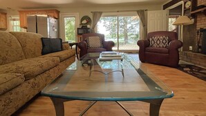 A living room with a sofa, armchairs, a coffee table, a fireplace, and a television.
