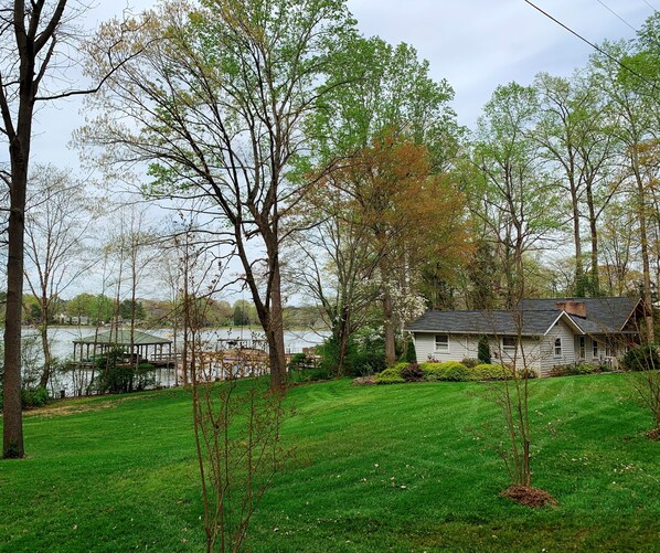 Une maison avec un toit en pente, entourée d’une pelouse bien entretenue et d’arbres.