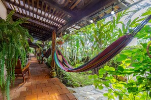 A covered outdoor area with a hammock, wooden benches, and lush greenery. - Cabañas Villa San Miguel (Alto Boquete)