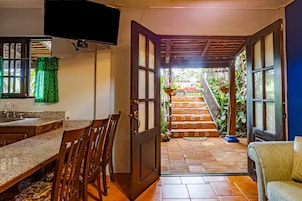 A kitchen with a granite countertop, wooden chairs, and a sink.
