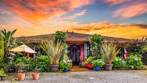 A house with a tiled roof, surrounded by lush greenery and potted plants.