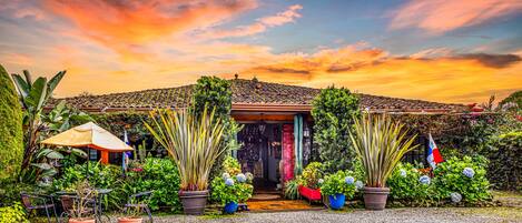 A house with a tiled roof, surrounded by lush greenery and potted plants.