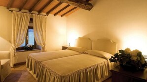 Un dormitorio con dos camas, una ventana con cortinas, una mesita de noche con lámpara y una silla.