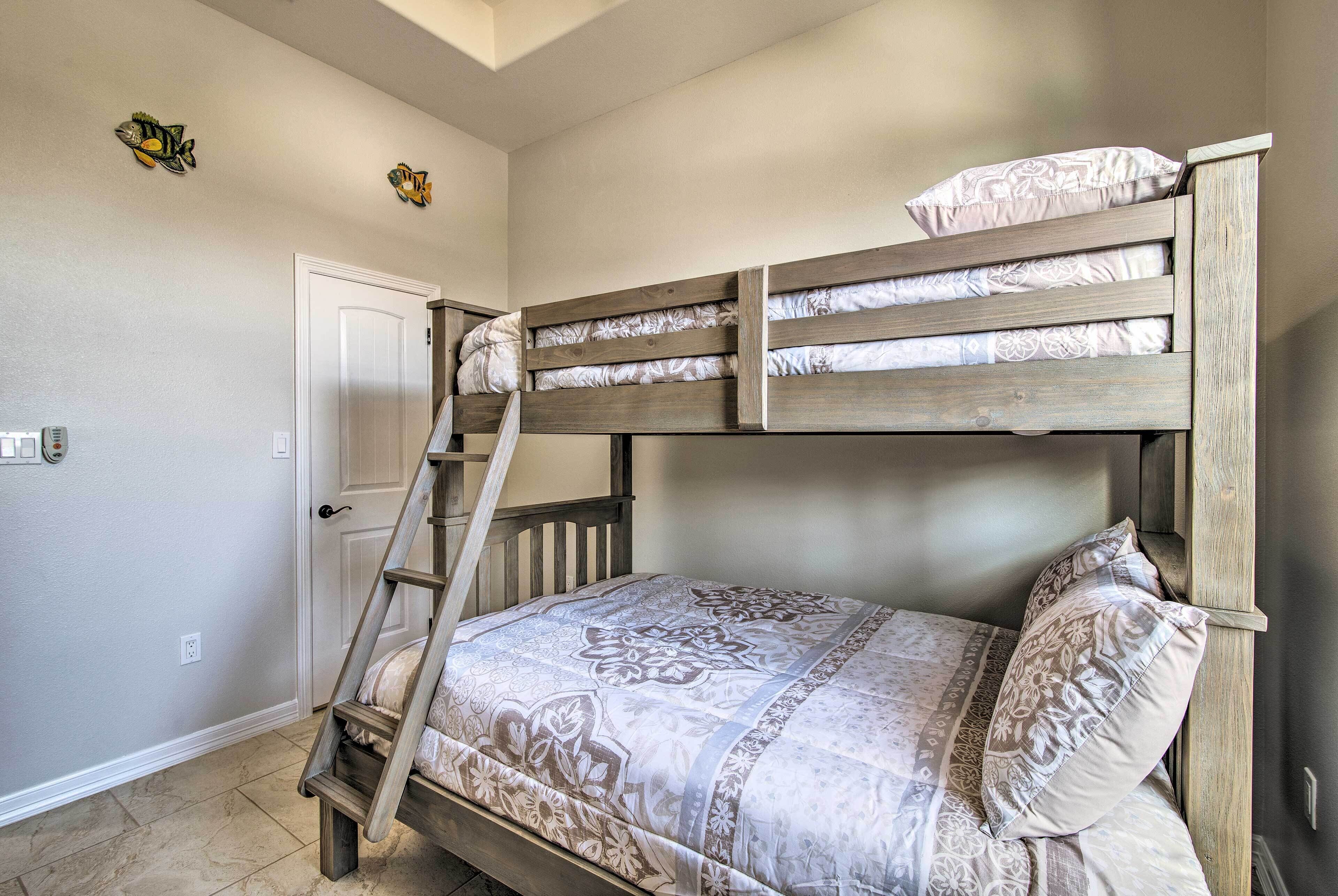 Een stapelbed met een ladder, een bed met een patroon erop, en een deur op de achtergrond.