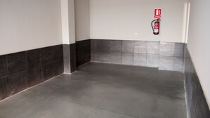 Un pasillo con paredes de baldosas oscuras y claras, un extintor en la pared y un piso limpio y brillante.
