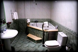 A bathroom with a bathtub, toilet, sink, and a bench. - La Siesta (Tordesillas)