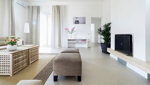 Un salon moderne avec un canapé, un pouf et un téléviseur à écran plat fixé au mur.