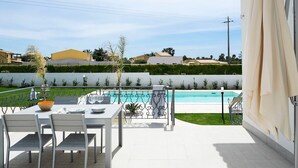 Une terrasse extérieure avec une table et des chaises, une piscine et une vue sur le quartier.