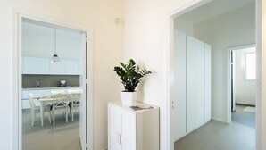 Un appartement moderne et minimaliste comprenant une cuisine, un coin repas et un couloir menant à une autre pièce.