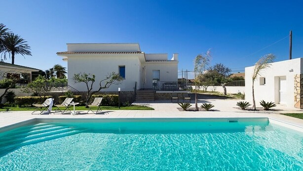 Une maison moderne dotée d’une piscine, d’un patio couvert et d’un jardin bien entretenu.