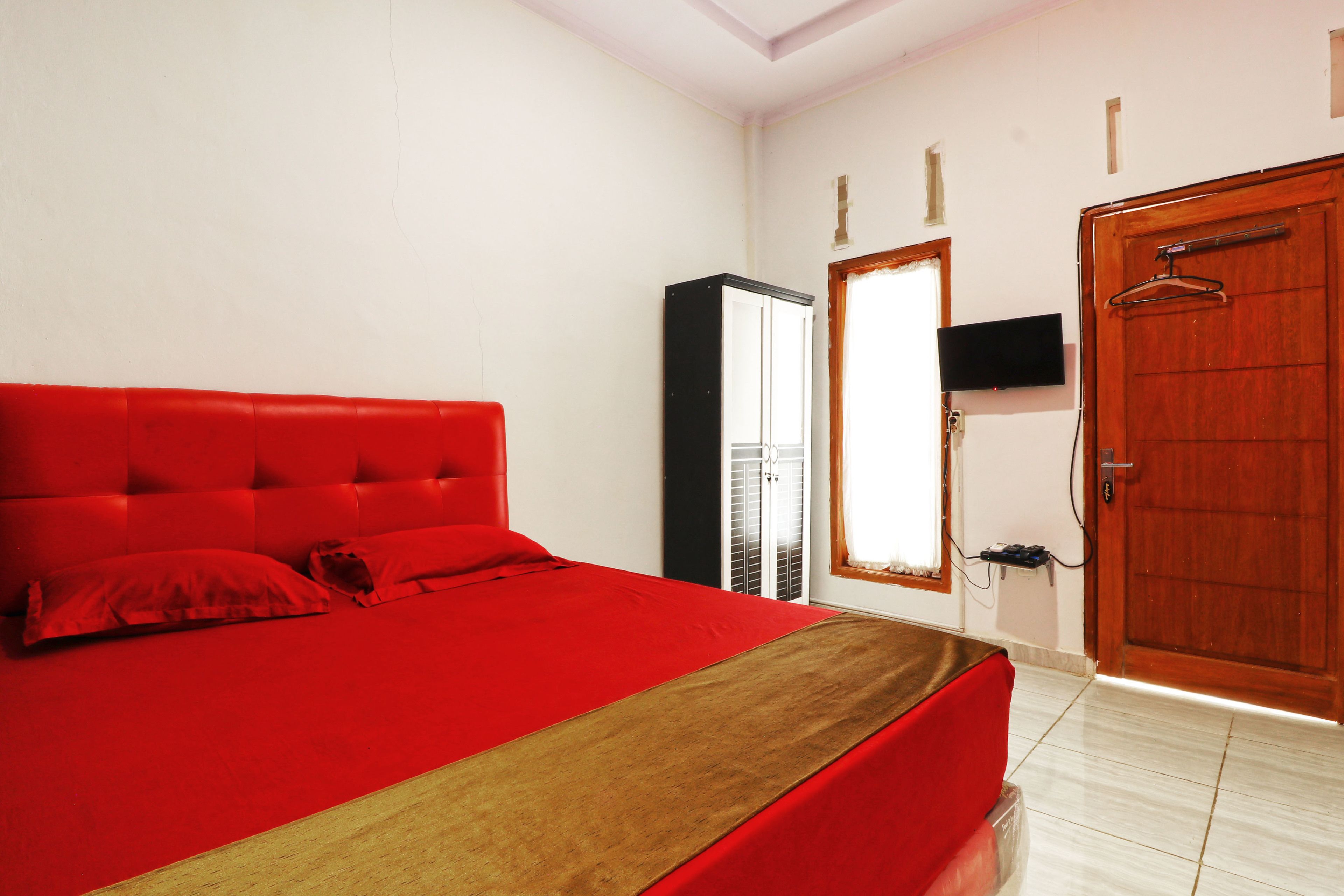Una camera da letto con una coperta rossa, una porta in legno e un armadio.