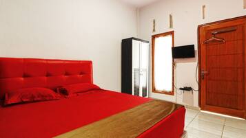 Una camera da letto con una coperta rossa, una porta in legno e un armadio.