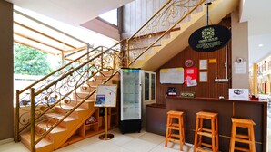 Ein Empfangsbereich mit Treppe, Holzschemeln, einer Rezeption und einem Schild mit dem Hotelnamen.
