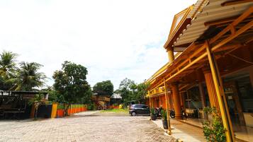 A hotel entrance with a paved driveway, a parked car, and a motorcycle.