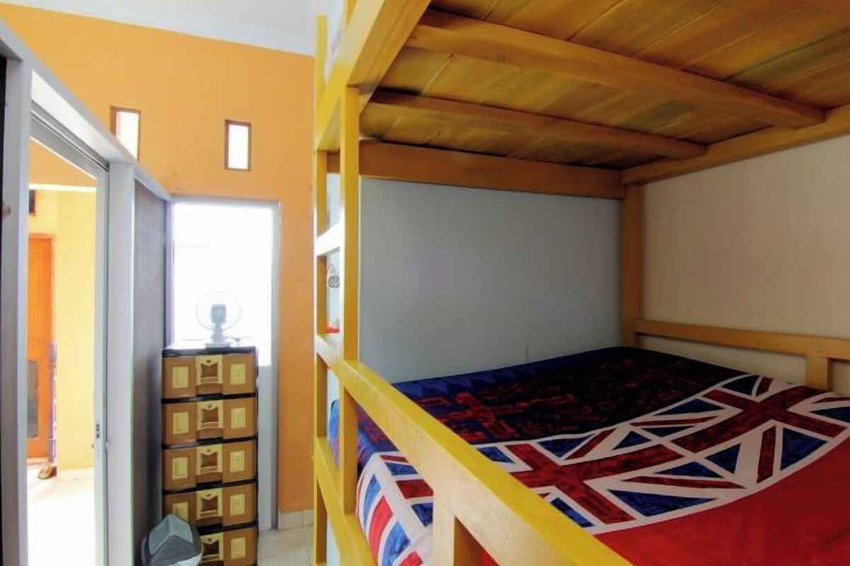 Ein Stockbett mit Union Jack Flagge, einem Holz-Kopfteil und einem Fenster mit Tageslicht.