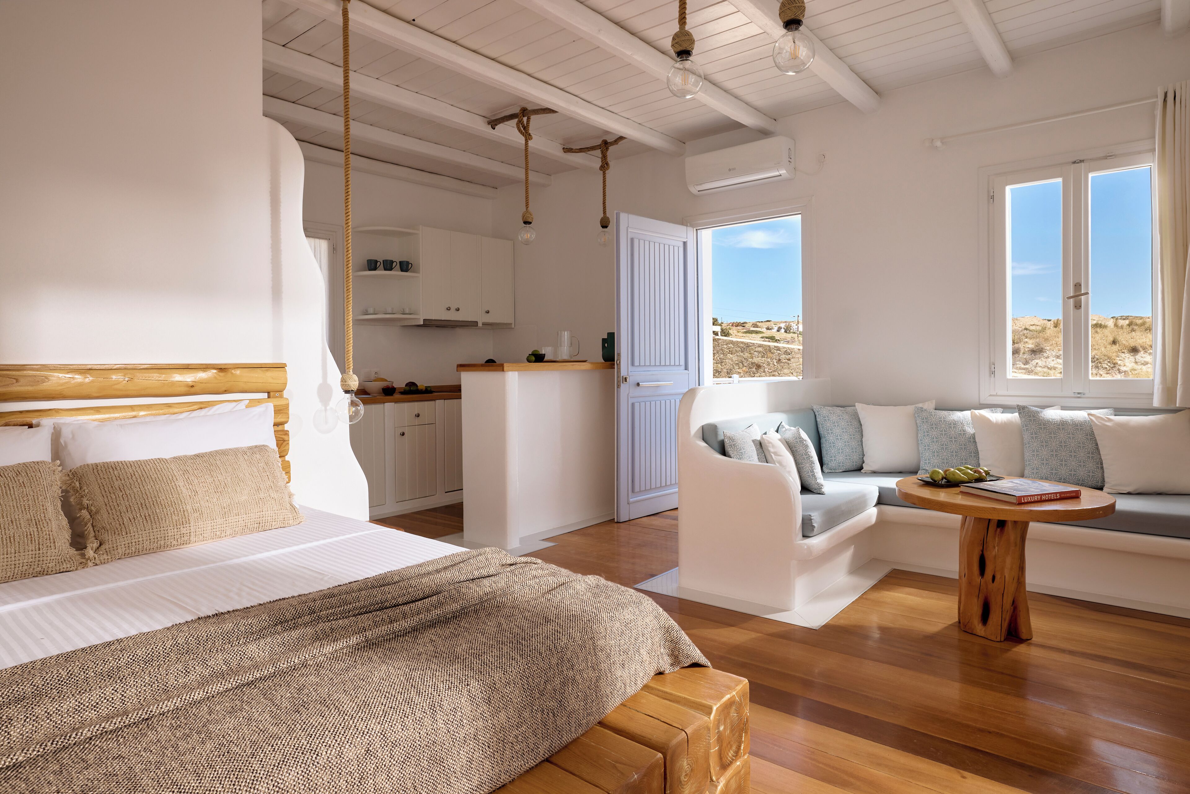 Une chambre à coucher avec un lit, un banc en bois, un canapé et une petite table.