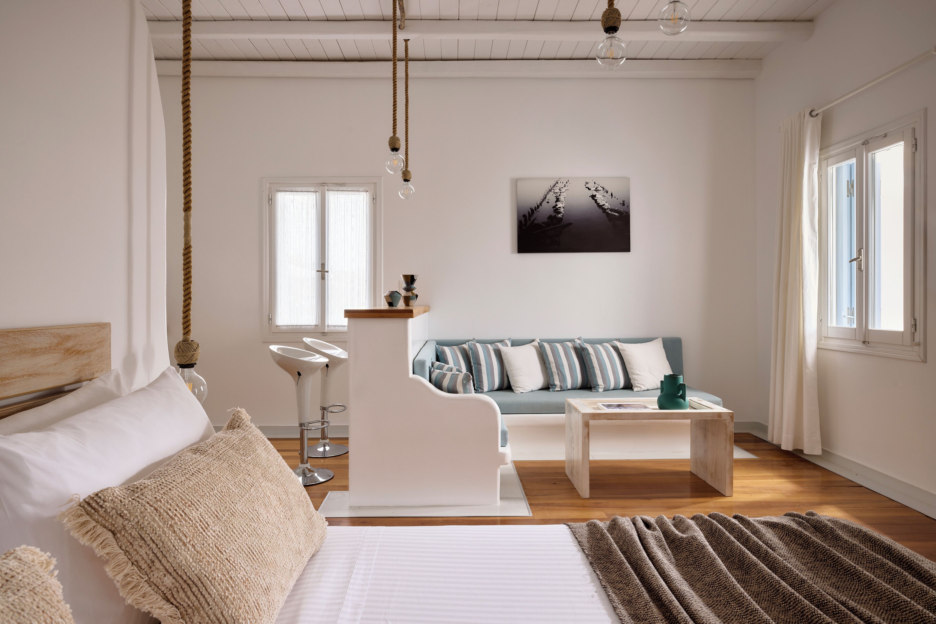 A bedroom with a bed, a bedside table, a nightstand, a sofa, a coffee table, and a wall-mounted picture.