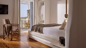 Une chambre à coucher avec un lit, une chaise, un téléviseur et une vue sur l’extérieur.