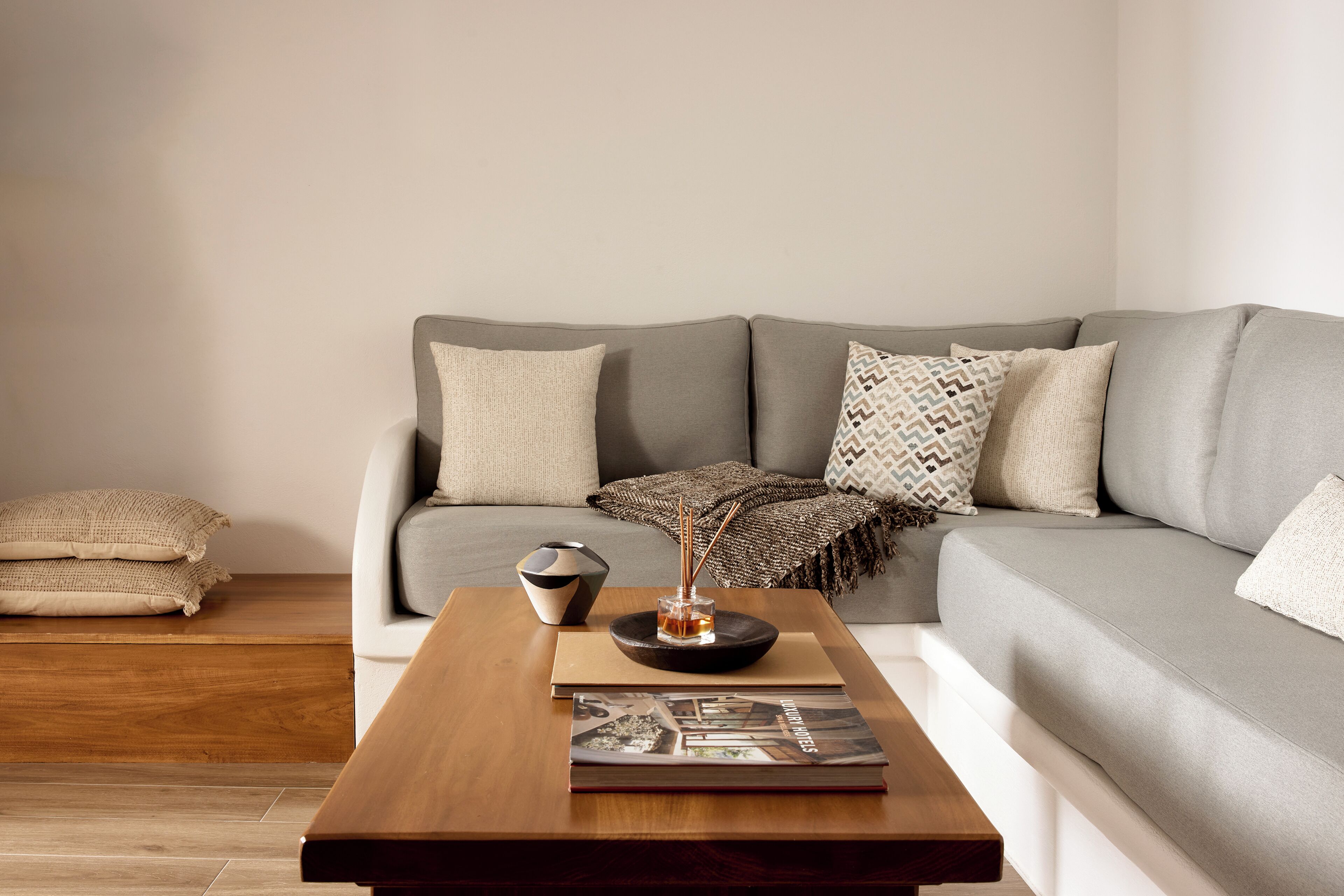 Ein modernes Wohnzimmer mit einem grauen Sofa, einem Holztisch und einer Zeitschrift.