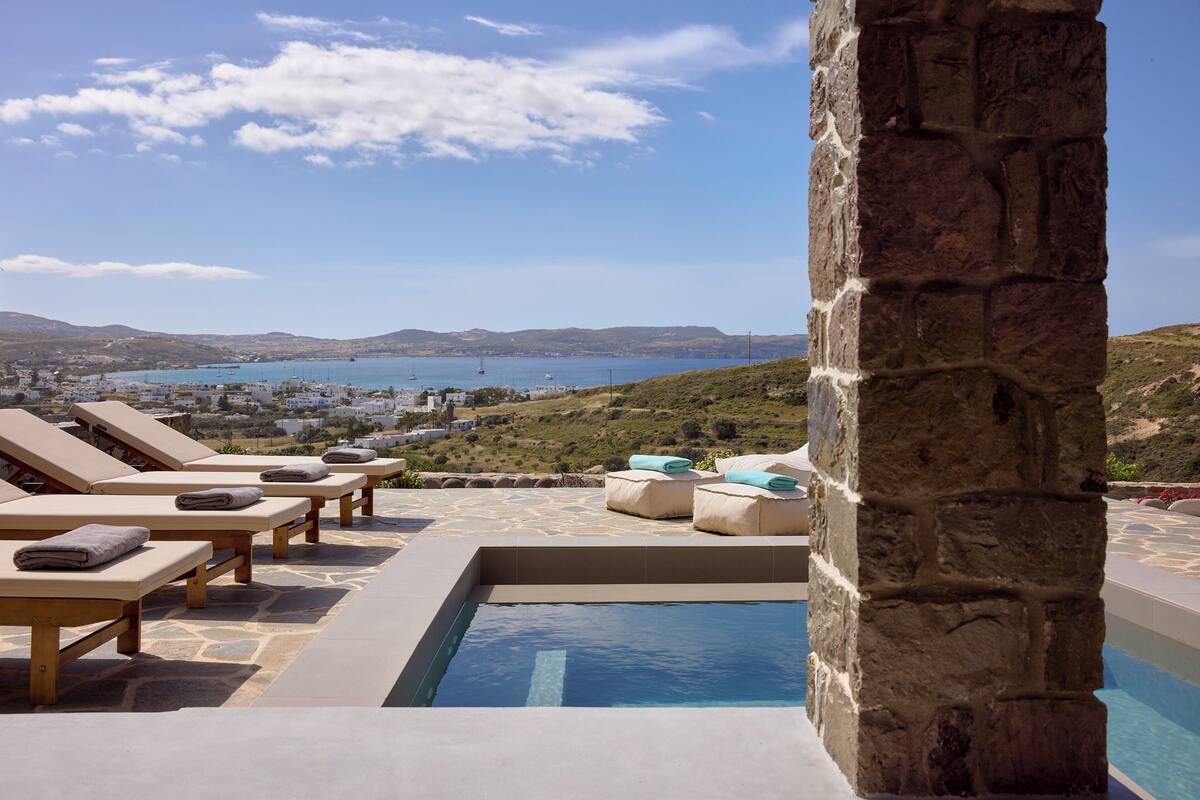 A pool area with lounge chairs and a stone pillar.