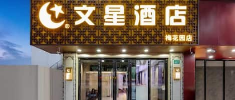 A hotel entrance with a prominent sign, glass doors, and a visible entrance area.