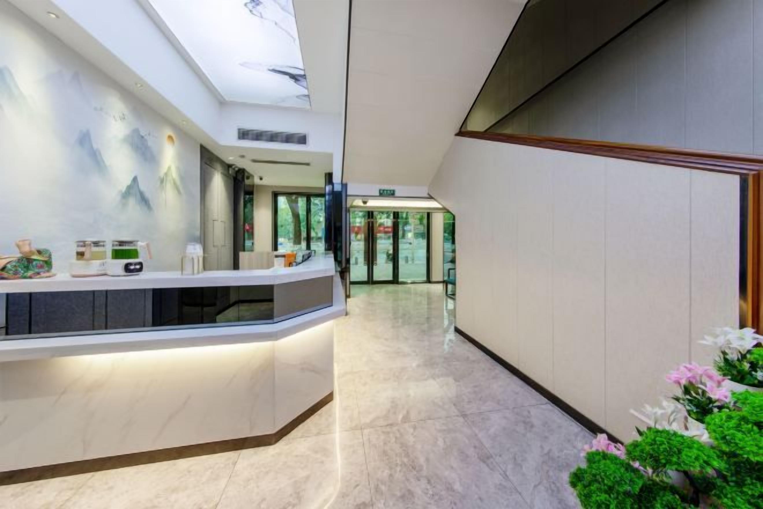 Zona de recepción de hotel con suelo de mármol, mostrador de recepción y vistas al vestíbulo.