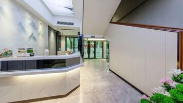 Zona de recepción de hotel con suelo de mármol, mostrador de recepción y vistas al vestíbulo.