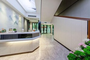 Área de recepção de hotel com piso de mármore, balcão de atendimento e vista para o saguão.