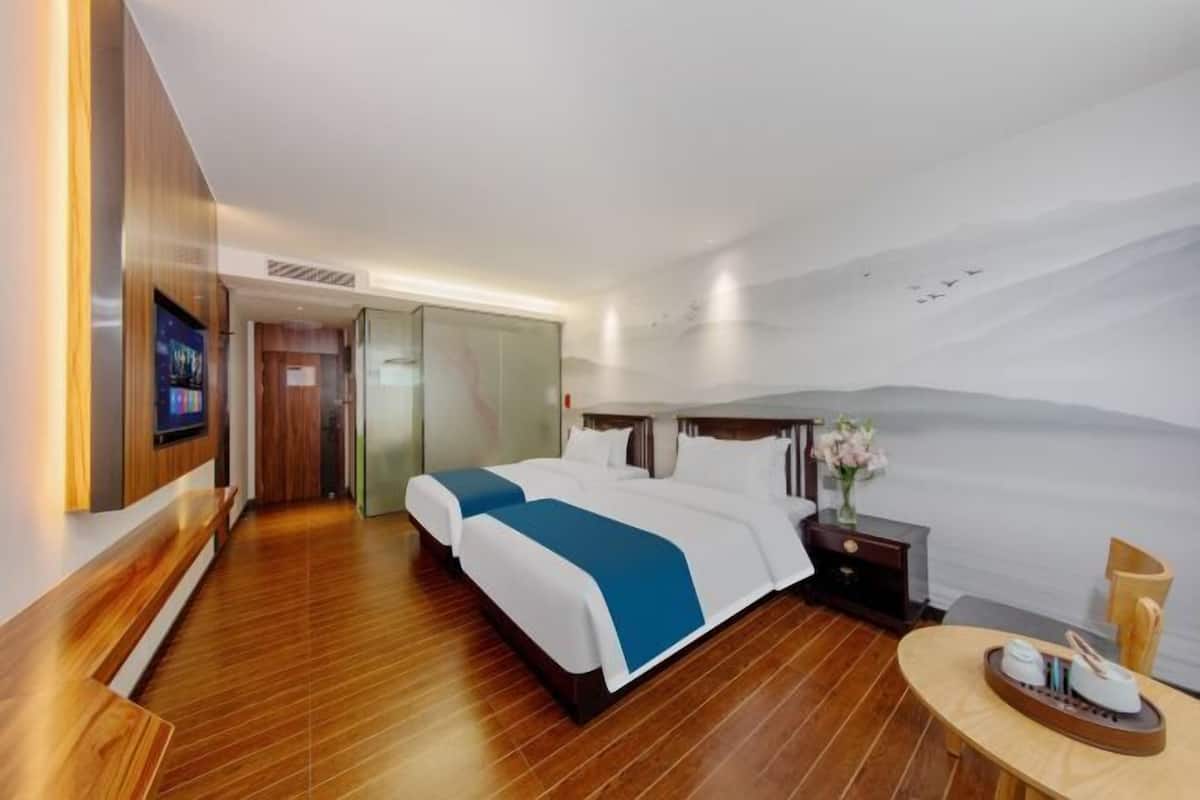 A hotel room with a bed, bedside table, and a view of the sea.