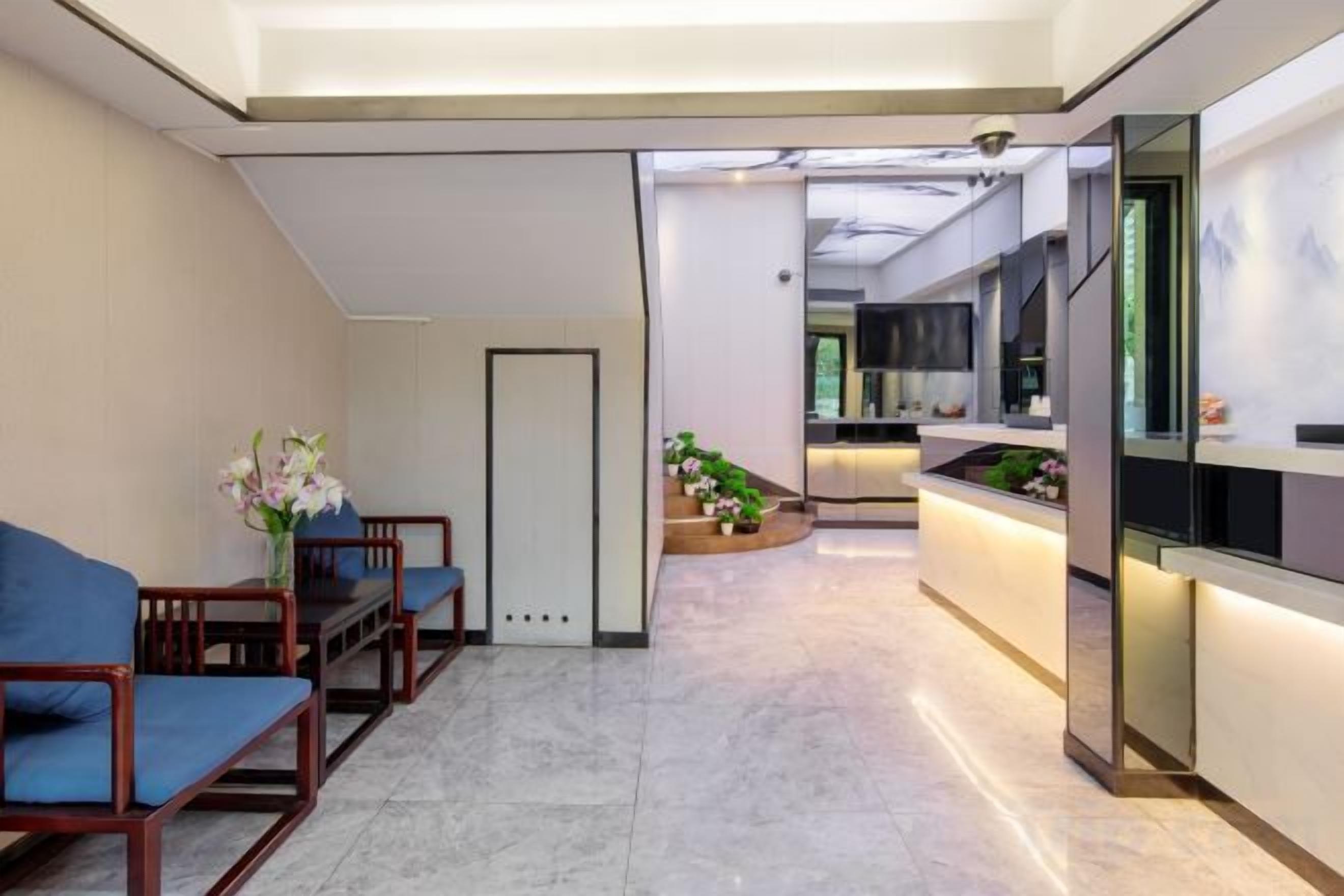 A modern hotel lobby with a reception desk, seating area, and a view into the kitchen.