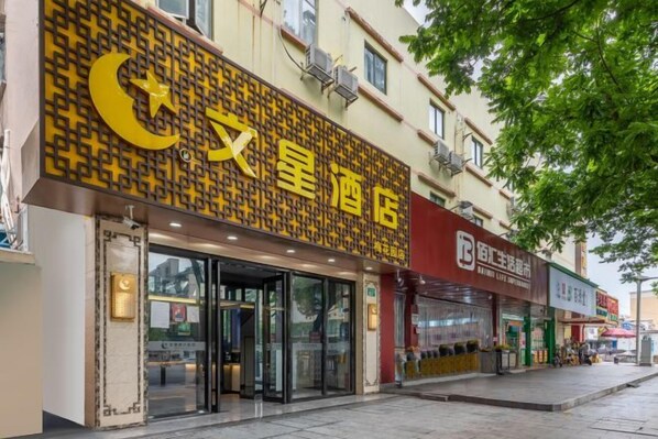 A hotel with a prominent yellow sign, a glass entrance, and a red awning.