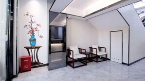 Ein modernes Interieur mit einer Sitzecke, einer Vase mit Blumen und einer roten Kiste auf dem Boden.