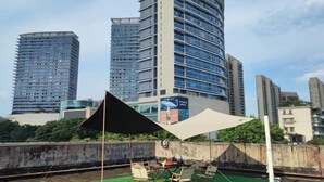 Eine Dachterrasse mit Tisch und Stühlen, umgeben von hohen Gebäuden.