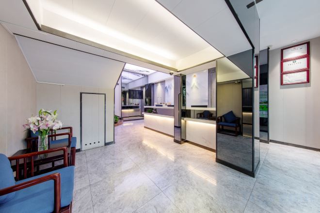 Un moderno vestíbulo de hotel con una recepción, zona de estar y un separador de vidrio.