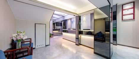 A modern hotel lobby with a reception desk, seating area, and a glass partition.