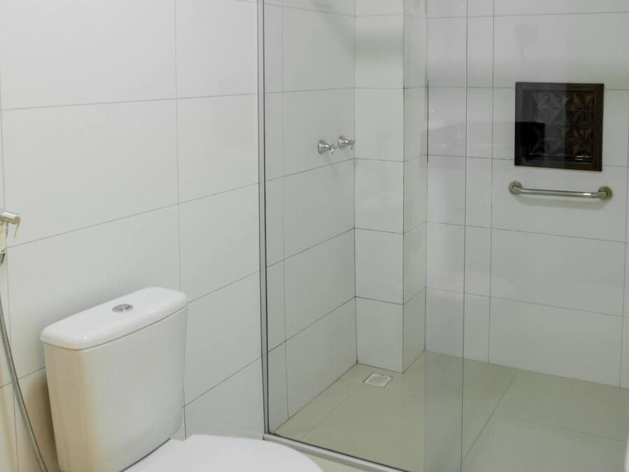 A bathroom with a toilet, a glass shower enclosure, and a small window.