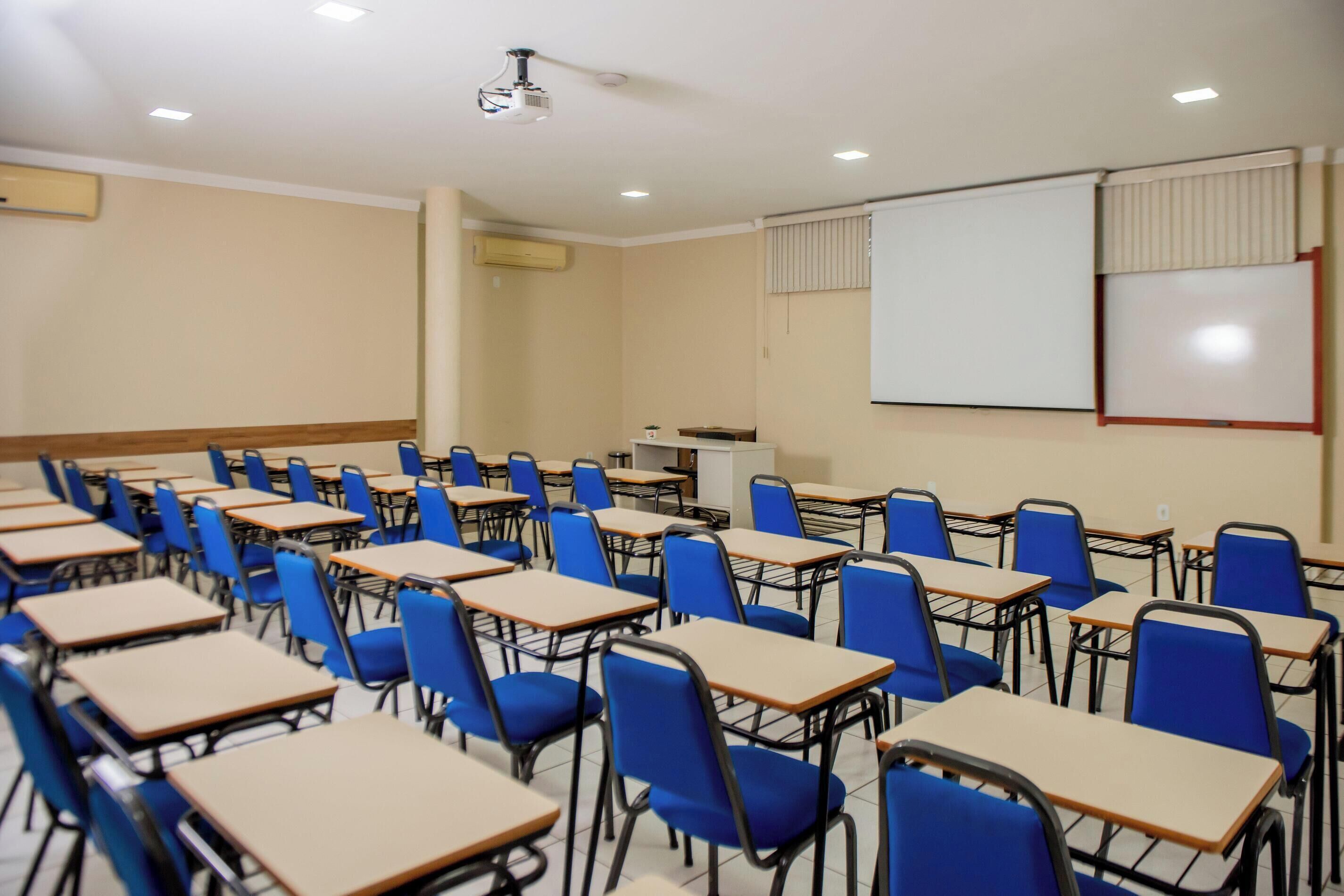 A classroom with rows of desks and chairs, a projector, and a whiteboard.