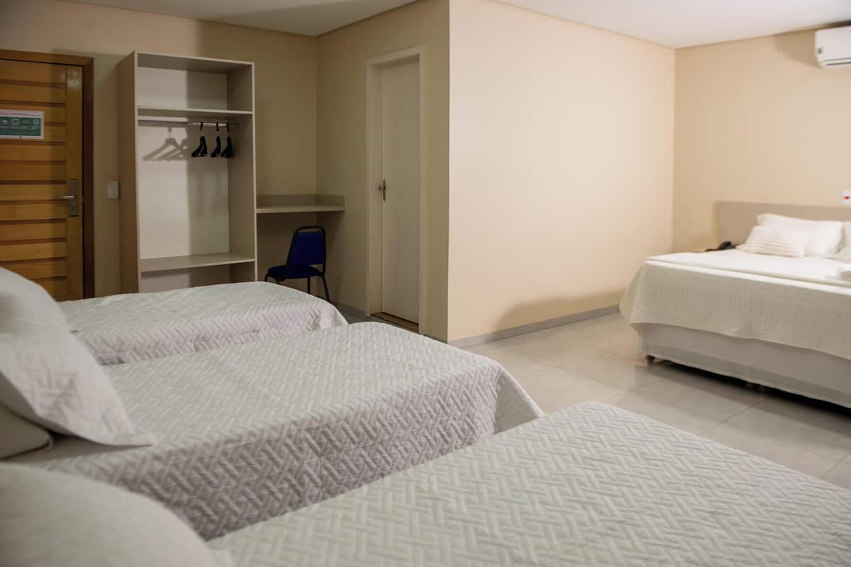 A hotel room with two beds, a wardrobe, and a chair.