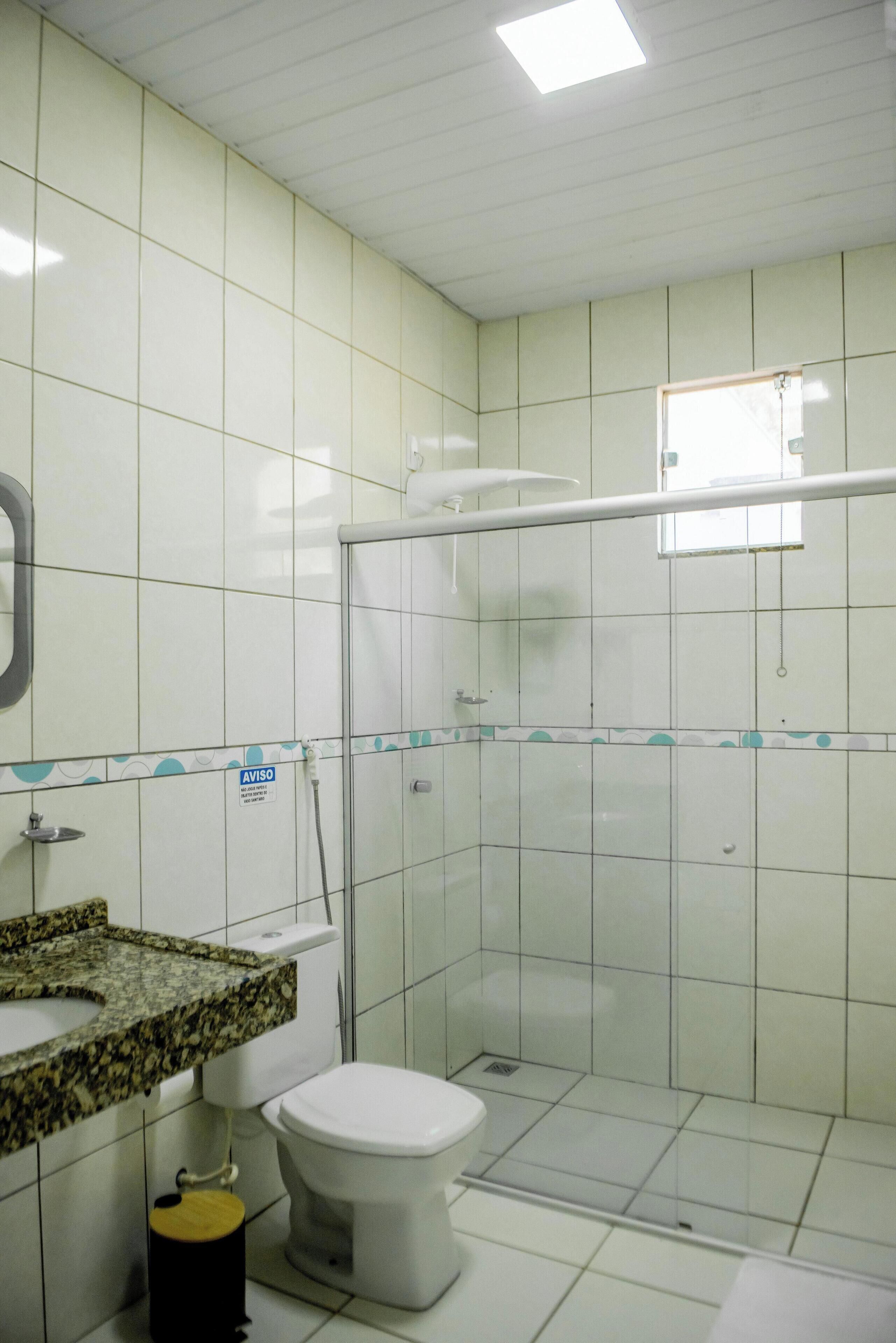 A bathroom with a toilet, a shower enclosure, and a sink with a granite countertop.