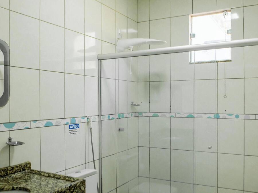 A bathroom with a toilet, a shower enclosure, and a sink with a granite countertop.