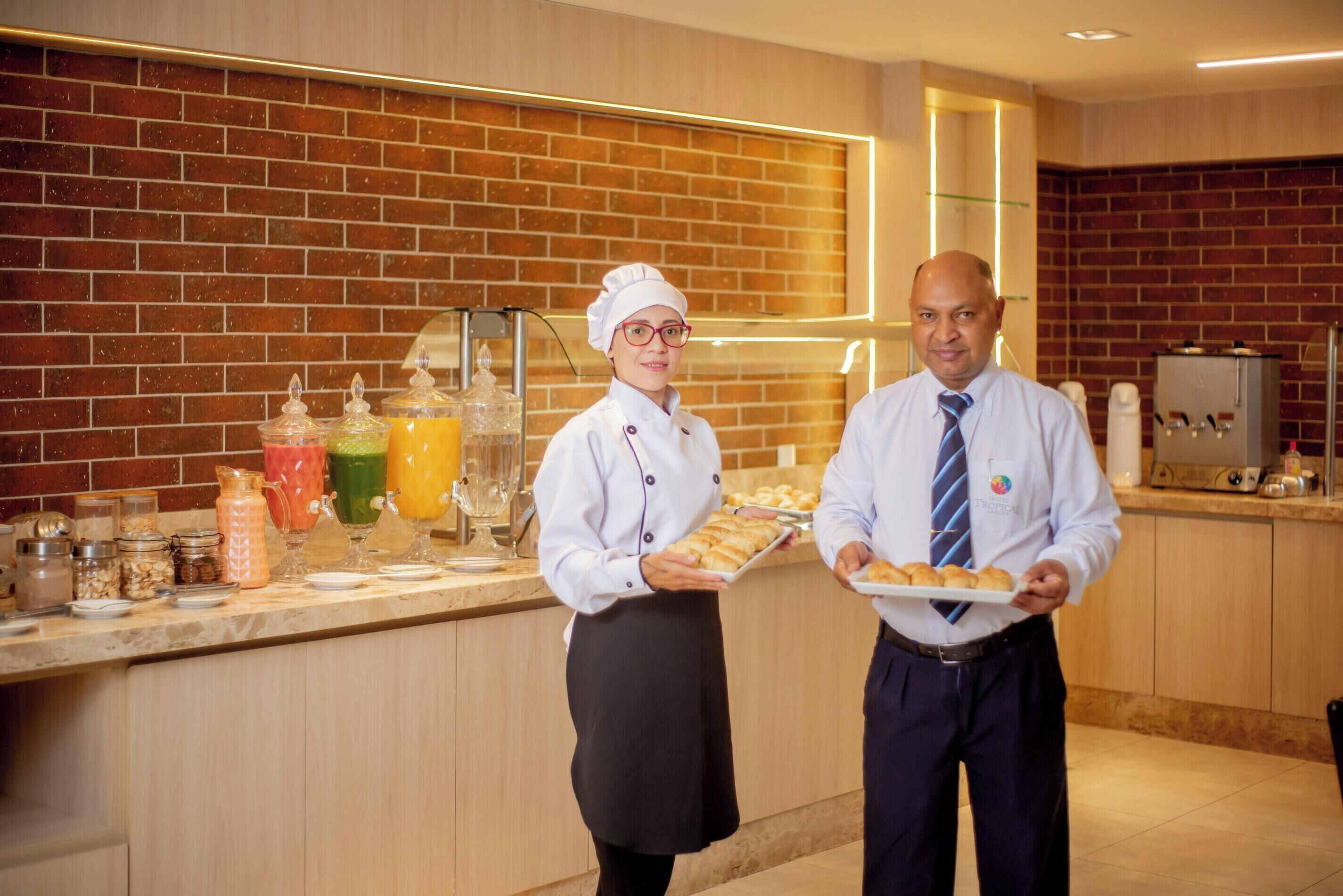 A kitchen area with a brick wall, a buffet counter with food items, and a coffee machine.